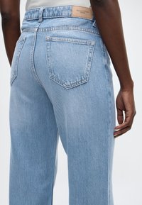 Φόρμα από ανοιχτό μπλε τζιν με ψηλή μέση, κλασικό σχέδιο με πέντε τσέπες και δερμάτινη ετικέτα στη πίσω ζώνη μέσης.