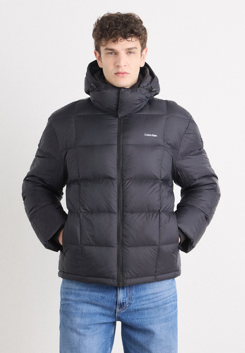 Must must jacket kõrge krae ja lukuga. Omab tikitud sektsioone ja logo vasakul rinnal. Kapuutsiga disain.