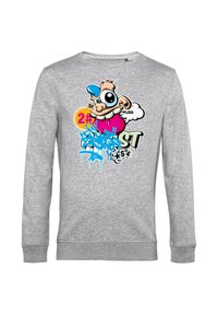 Maglietta grigia a maniche lunghe con un volto di cartone animato colorato che presenta una grande lingua, un cappellino blu e testo e simboli in stile graffiti sulla parte anteriore.