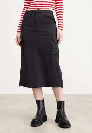 Jupe midi noire en tissu léger, dotée d'une taille élastique et de deux grandes poches latérales. Texture lisse avec une coupe droite.