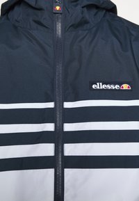 Veste de marine avec zip sur le devant, dotée d'une capuche, de rayures blanches horizontales et d'un logo brodé sur la poitrine avec un design circulaire.