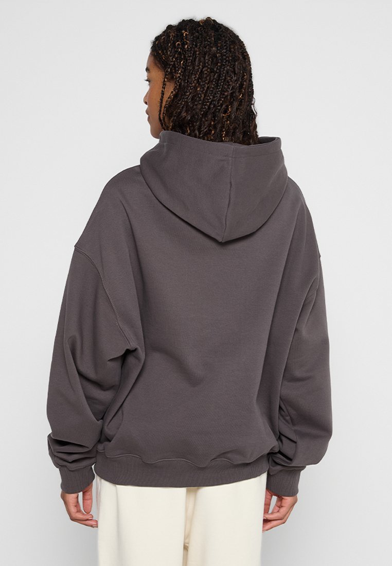 Oversized bluza z kapturem w kolorze węgla, z przestronnym kapturem, opuszczonymi ramionami oraz ściągaczami na mankietach i dole; wykonana z miękkiego materiału bawełnianego w luźnym kroju.