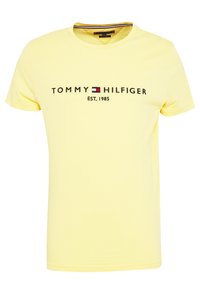 T-shirt en coton jaune avec un col rond, arborant le texte et le logo noir "TOMMY HILFIGER", avec "EST. 1985" imprimé en dessous. Texture lisse.
