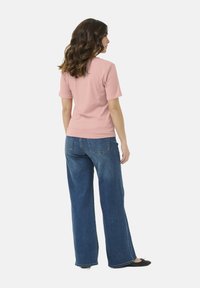 Top de manga corta de canalé en rosa claro combinado con vaqueros de denim azul de pierna ancha. Textura suave, ajuste relajado y piernas de corte recto.