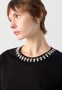 Must must, mille pehmema tekstuuriga ja klassikalise disainiga, kaunistatud hõbedaste rhinestone kraega, millel on marquise kuju nüansid.
