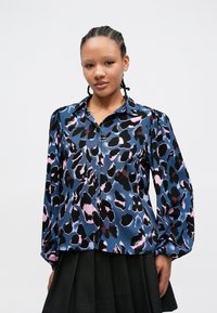Langermet skjorte med knapper i blått satengstoff med svart og rosa abstrakt leopardmønster; har klassisk krage og rynkede ermer.