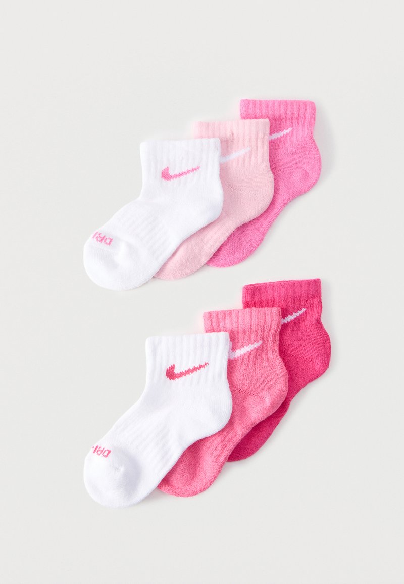 Dos juegos de tres calcetines tobilleros en blanco, rosa claro y rosa oscuro, cada uno con un logo Nike swoosh en contraste.