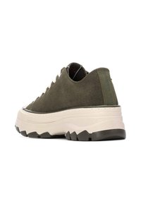 Zapatillas de gamuza verde olivo con una gruesa suela blanca intermedia, suela exterior texturizada negra y acentos en beige contrastantes. Presentan un frente con cordones y una lengüeta trasera.