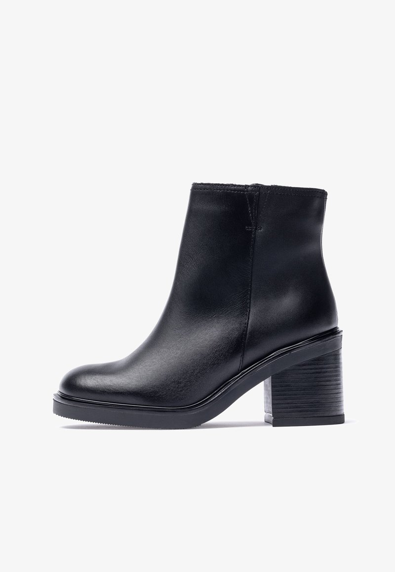 Schwarzer Leder-Stiefelette mit glatter Oberfläche, abgerundeter Zehe und klobigem, strukturiertem Absatz. Minimalistisches Design mit verstärkten Nähten.