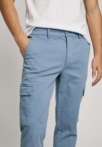 Light blue cargo pants with a textured fabric, featuring side pockets and a straight cut. The waistband has a button closure.