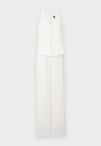 Άσπλο αμάνικο γιλέκο με ένα κουμπί και ταιριαστό παντελόνι φαρδιάς γραμμής, παρουσιάζονται σε απλό, φωτεινό φόντο.