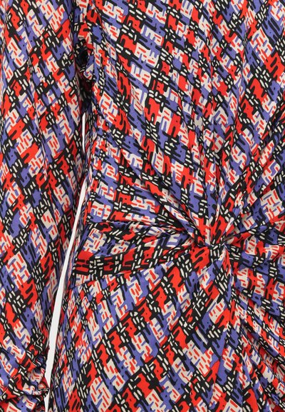 Vestido multicolorido com um padrão geométrico em vermelho, preto, lavanda e branco. O tecido é suave, com um detalhe torcido na cintura.