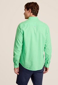 Groen lange mouwen shirt gemaakt van gestructureerde stof, met een kraag, knoopmanchetten en een afgeronde zoom. Kleine logo-opdruk op de achterkant.