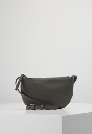 Small dark gray leather crossbody bag with adjustable strap and zipper closure on a white surface against light gray background.