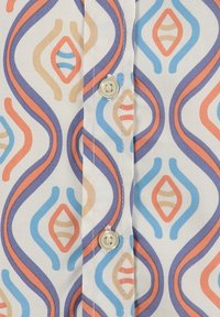 Camisa de algodón con un patrón ondulado colorido en azul, coral y beige, con un fondo blanco y un detalle de botón crema en el placket.