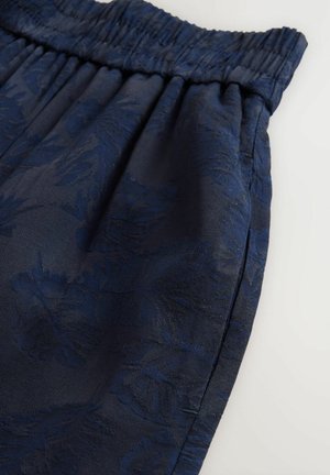 Dunkelblaue Shorts mit Gummibund, aus strukturiertem Stoff mit einem dezenten Blumenmuster. Mit seitlichen Taschen ausgestattet.