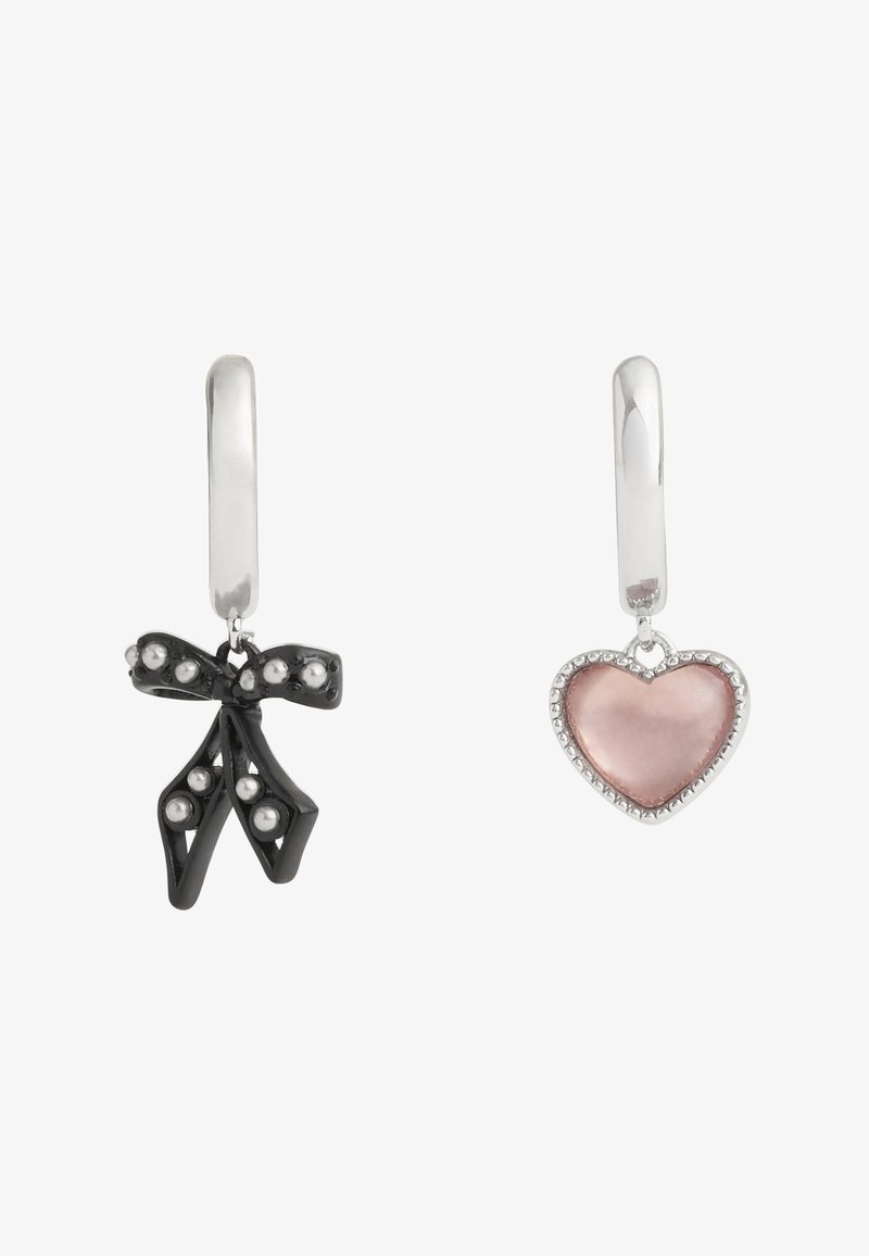 Boucles d’oreilles créoles en argent avec breloques dépareillées ; un nœud noir avec perles argentées, l’autre un cœur rose bordé d’argent.