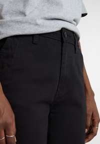 Zwarte denim jeans met een aansluitend ontwerp, voorzien van een knoopsluiting, riemlussen en zijzakken. Soepele textuur en klassieke stijl.