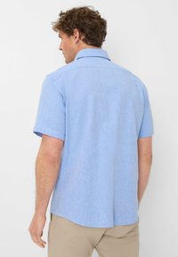 Korte mouw shirt van lichtblauwe stof met een gestructureerde afwerking. Bevat een klassieke kraag en een rechte zoom. Subtiele zijsplitsen voor extra comfort.