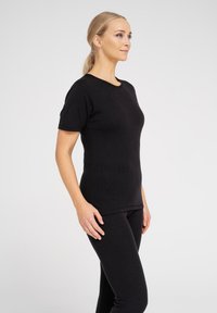 Black short-sleeve shirt made of ribbed fabric, fitted design with a round neckline, paired with matching black leggings.
