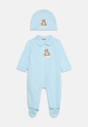 Lyseblå babyheldragt med foddækkende og matchende hat, begge med et lille bamse design foran.