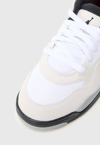 Λευκό και κρεμ αθλητικό παπούτσι με υλικά από δίχτυ και σουέτ, στρογγυλεμένη μύτη και μαύρες λεπτομέρειες στη λαστιχένια σόλα και τη γλώσσα.