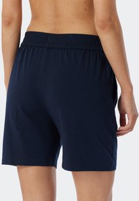 Mörkblå shorts med elastisk midja i ett mjukt, slätt tyg med en avslappnad passform, som når till mitten av låret, minimalistisk design utan mönster.