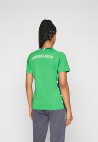 Roheline spordisärk lühikeste varrukatega, millel seljal on kirjas "MÖNCHENGLADBACH" ja külgedel kamuflaažimuster. Sile tekstuur.