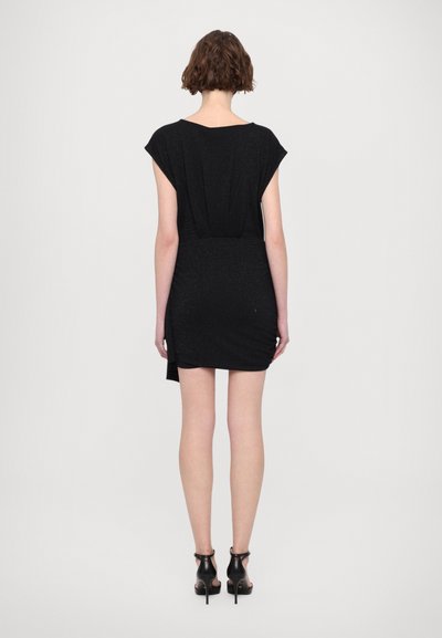 Robe noire à manches courtes, design ajusté et éclat subtil. L'arrière présente un détail plissé et un ourlet asymétrique, associé à des talons noirs.
