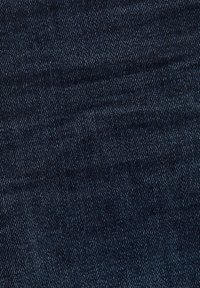 Mörk indigo denimtyg med en mjuk textur, som har ett subtilt diagonalt vävmönster och en lätt lyster.