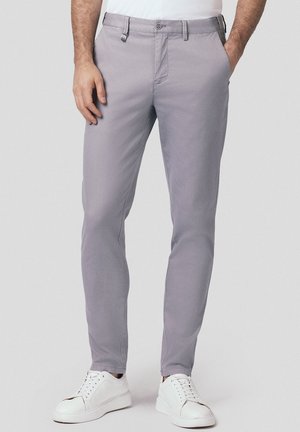 Szare chinosy o slim fit, wykonane z lekkiego bawełnianego materiału, z szlufkami na pasek i zapięciem na guzik. W połączeniu z białymi trampkami.
