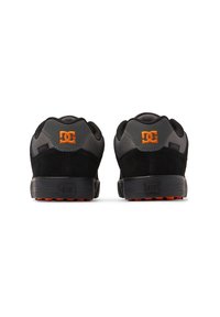 Black and gray back view of DC shoes with suede and mesh upper, featuring orange logo accents and a textured black rubber sole.