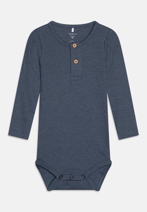 Modra dolga bodysuit iz rebraste tkanine, opremljena z henley ovratnikom z dvema lesenima gumboma in s pritrdilnimi zapiranji na dnu.