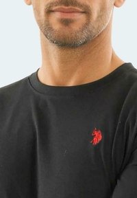 Black cotton t-shirt featuring a small red embroidered horse logo on the left chest, with a classic crew neck design and short sleeves.