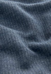 Mörkblå texturerad tyg med en mjuk, ribbad yta, som visar subtila färgvariationer och ett vågigt mönster skapat av veck.