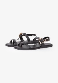 Zwarte platte sandalen met meerdere slanke banden en een gespdetail, gemaakt van glad synthetisch materiaal met een matte afwerking.