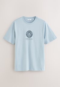 Lichtblauw T-shirt met korte mouwen en ronde hals, met een cirkelvormige zonsondergang- en oceaangrafiek en de tekst "Chasing Blue Echoes" op de borst.