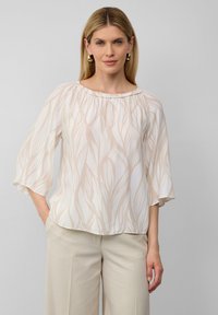 Leichte, cremige Bluse mit fließendem Design und beigen Blattmustern. Verfügt über einen gerafften Halsausschnitt und weite, ellebogenlange Ärmel.