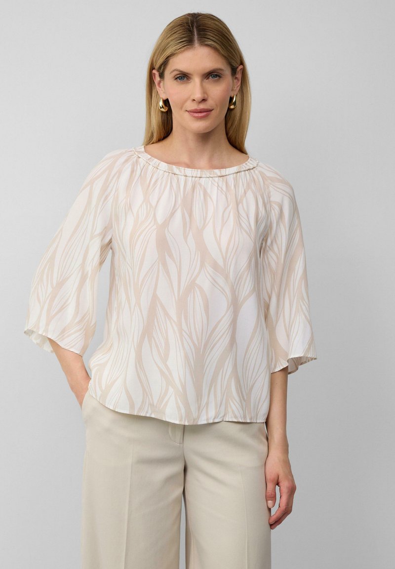 Leichte, cremige Bluse mit fließendem Design und beigen Blattmustern. Verfügt über einen gerafften Halsausschnitt und weite, ellebogenlange Ärmel.