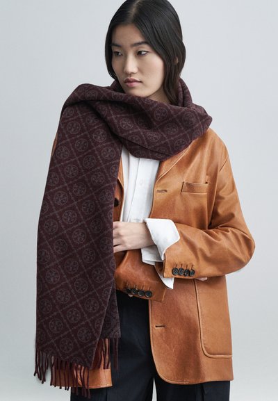 Burgundy-mönstrad scarf i mjukt tyg, med intrikata mönster och fransar, bärs över en beige läderjacka.