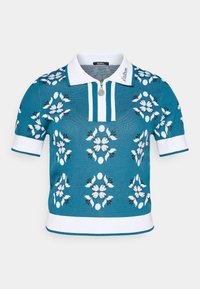 Teal strikket polo skjorte med hvite aksenter, front glidelås, og blomster mønster i hvit, lyseblå, og svart. Korte ermer med ribbede manchetter.
