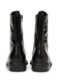 Pair of black leather ankle boots with back zippers, visible stitching, and stacked low heels shown from the rear on white background.