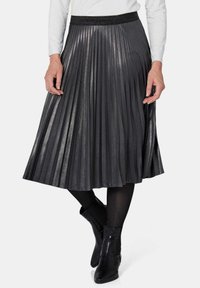 Plissé midi-rok in donkergrijs met een subtiele glans, voorzien van een gestructureerde zwarte tailleband, gecombineerd met zwarte enkellaarsjes en maillots.