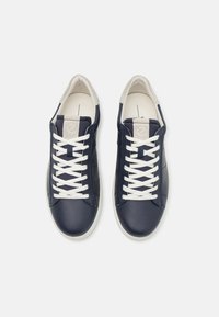 Baskets en cuir bleu marine avec des lacets blancs, présentant une texture lisse et un design minimaliste. Bout arrondi et semelle intérieure rembourrée.