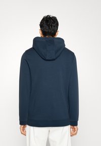 Felpa con cappuccio blu navy dal taglio morbido, maniche lunghe e design semplice. Tessuto morbido con polsini e bordo a costine.