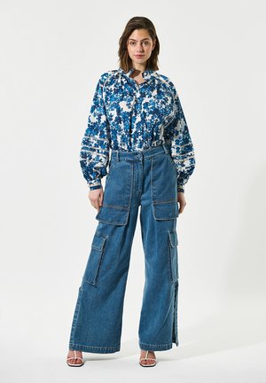 Bloemmotief blouse in blauw en wit, met ruime mouwen; gecombineerd met hooggetailleerde, wijde lichtblauwe denim cargobroeken.