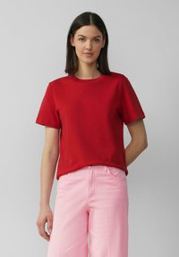 Rode katoen T-shirt met een ronde halslijn en korte mouwen, gecombineerd met lichtroze broeken. Eenvoudig ontwerp, gladde textuur en casual pasvorm.