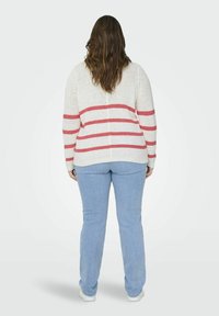 Maglione leggero a maglia bianca con righe orizzontali rosse, abbinato a jeans azzurri chiari e sneaker bianche. Caratterizzato da una vestibilità morbida e maniche lunghe.