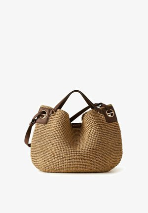 Borsa tote in paglia intrecciata color sabbia con manici in pelle marrone scuro, occhielli dorati e tracolla regolabile.