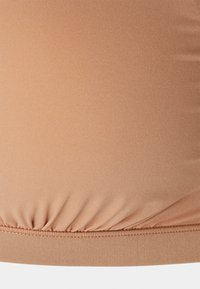 Tissu stretch nude avec une texture lisse, présentant des détails froncés à l'ourlet et un design ajusté.